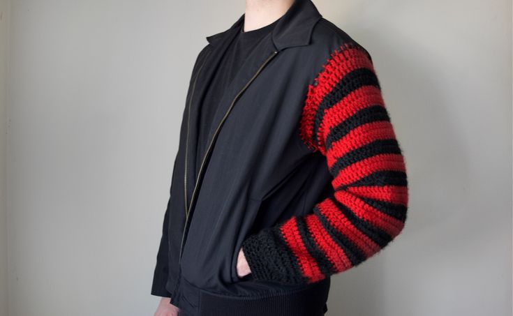 a young man wearing a black and red striped jacket with his hands in his pockets