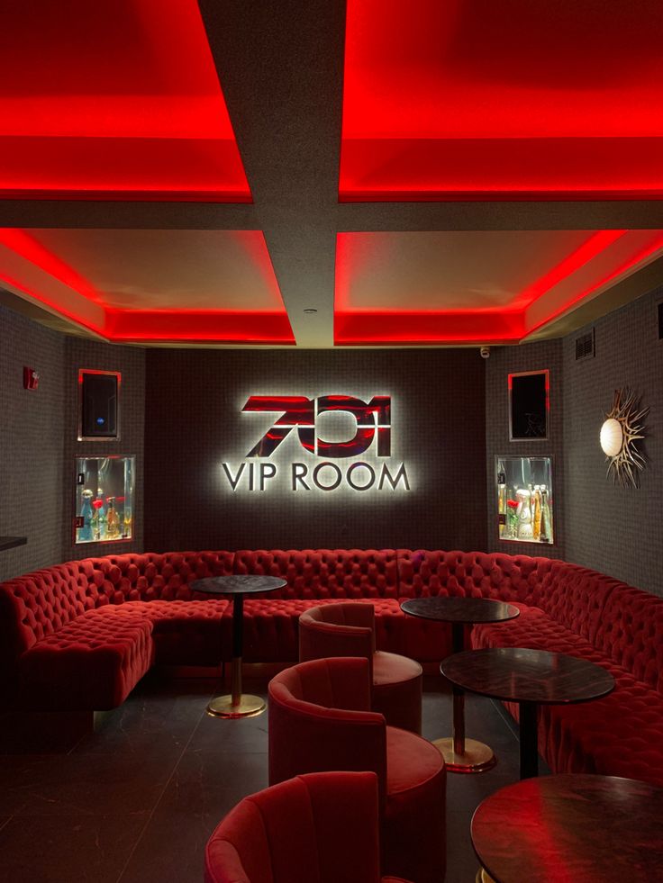 a room with red couches and tables in front of a neon sign that reads, vrp room