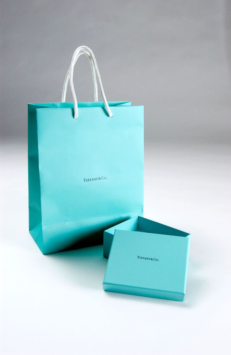 a blue shopping bag sitting on top of a white table next to an empty box