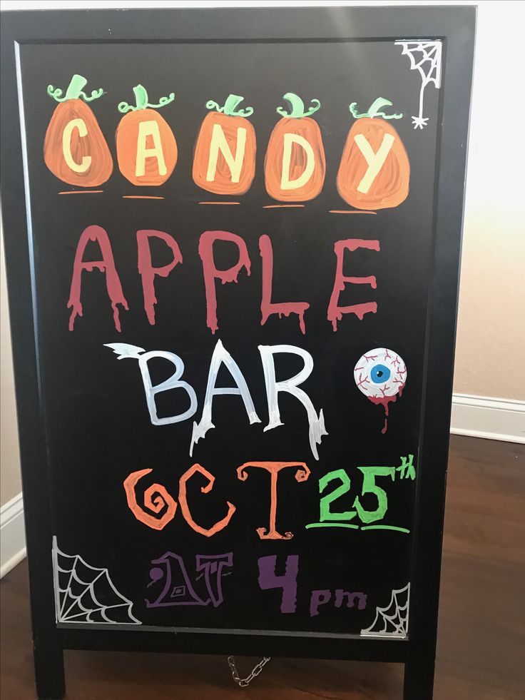 a candy apple bar sign is decorated with chalk and spooky decorations for halloween