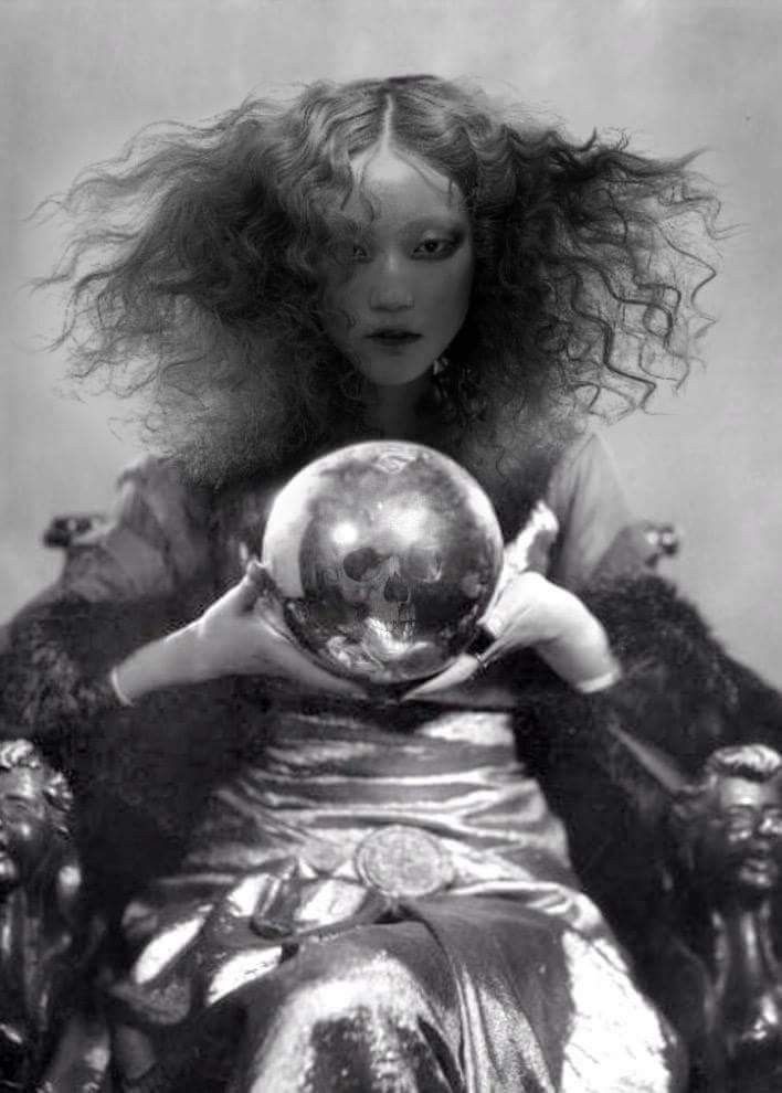 a woman holding a crystal ball in her hands and sitting on a chair with long hair