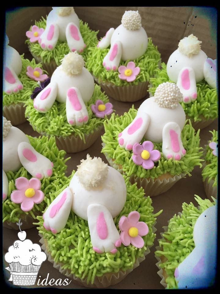 cupcakes decorated with white frosting and pink flowers are arranged in the shape of rabbits