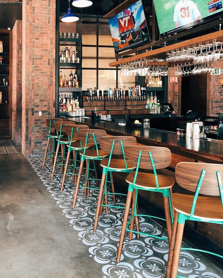 a bar with wooden chairs and televisions on the wall