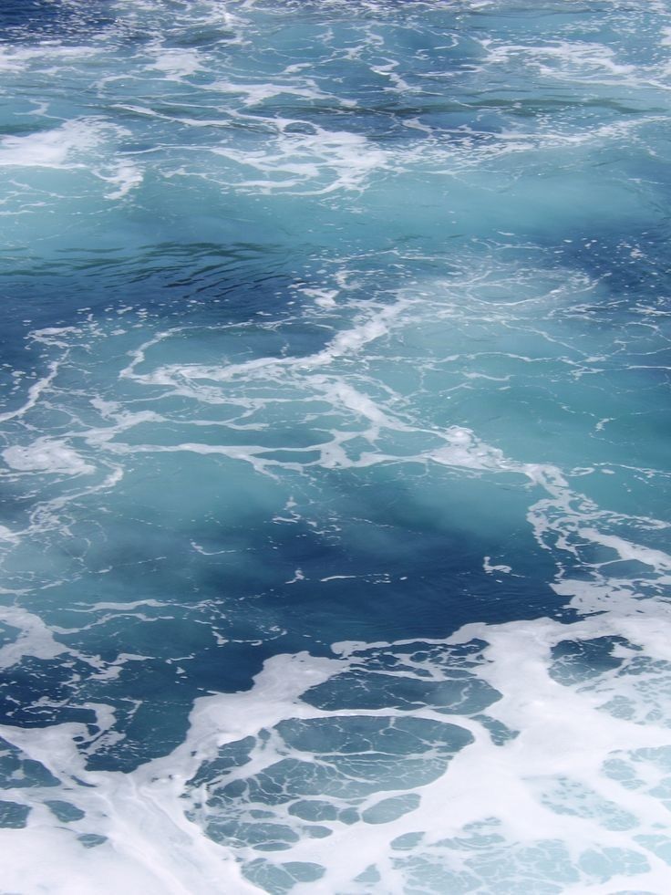 the water is blue and foamy as it moves through the ocean with small waves