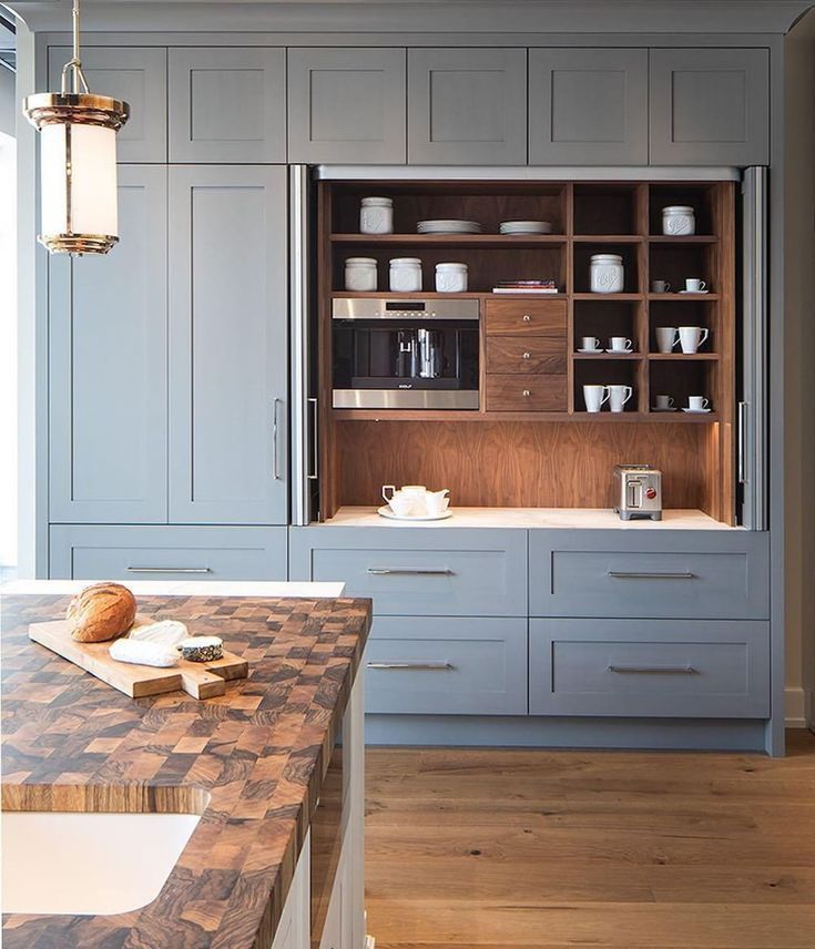 a kitchen with gray cabinets and wooden counter tops