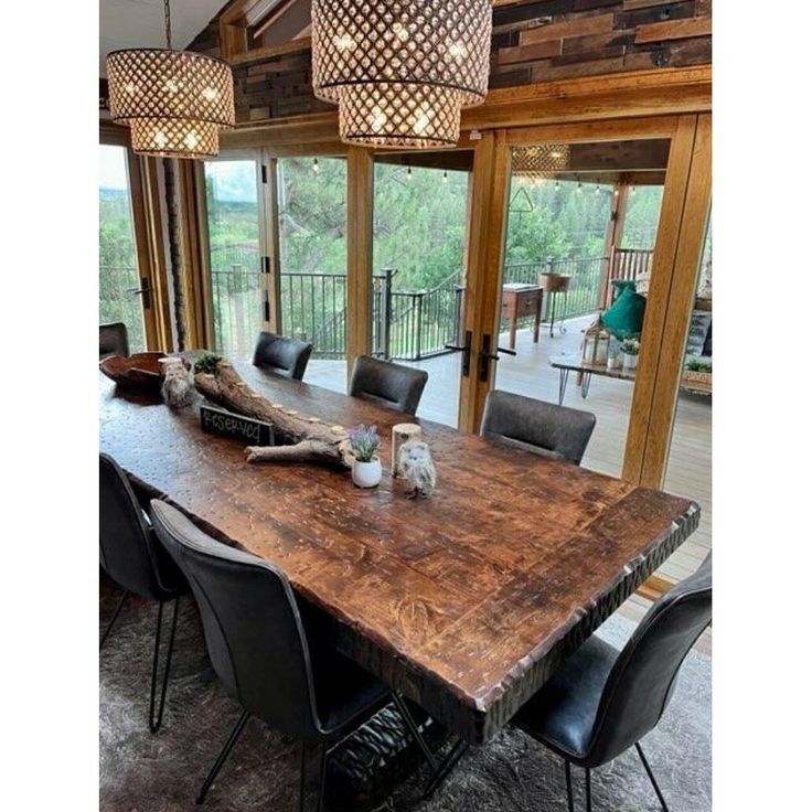 a large wooden table surrounded by black leather chairs and chandelier hanging from the ceiling