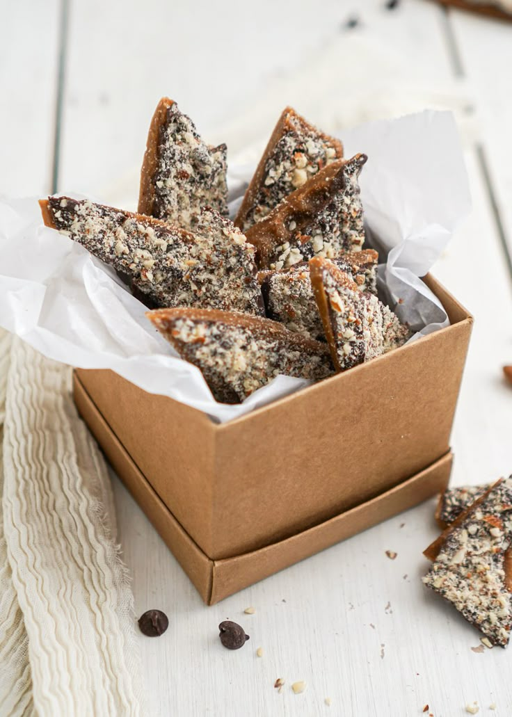 a box filled with pieces of food sitting on top of a white wooden table next to a napkin