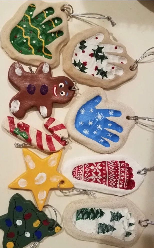 christmas ornaments are hanging on a table together, including one with a handprinted ornament