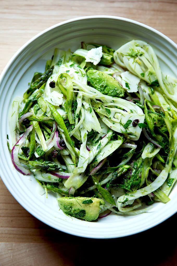 a white bowl filled with broccoli and other vegetables on top of a wooden table