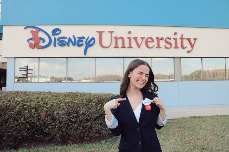 a woman standing in front of the disney university sign