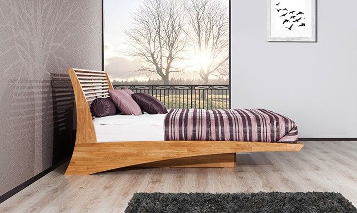 a wooden bed sitting on top of a hard wood floor next to a white wall