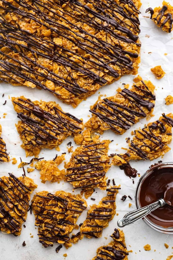 chocolate and caramel granola bars on parchment paper next to a jar of peanut butter