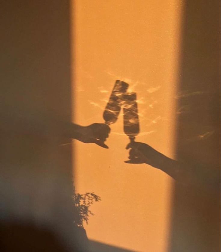 the shadow of two people holding their hands in front of a window with sunlight coming through