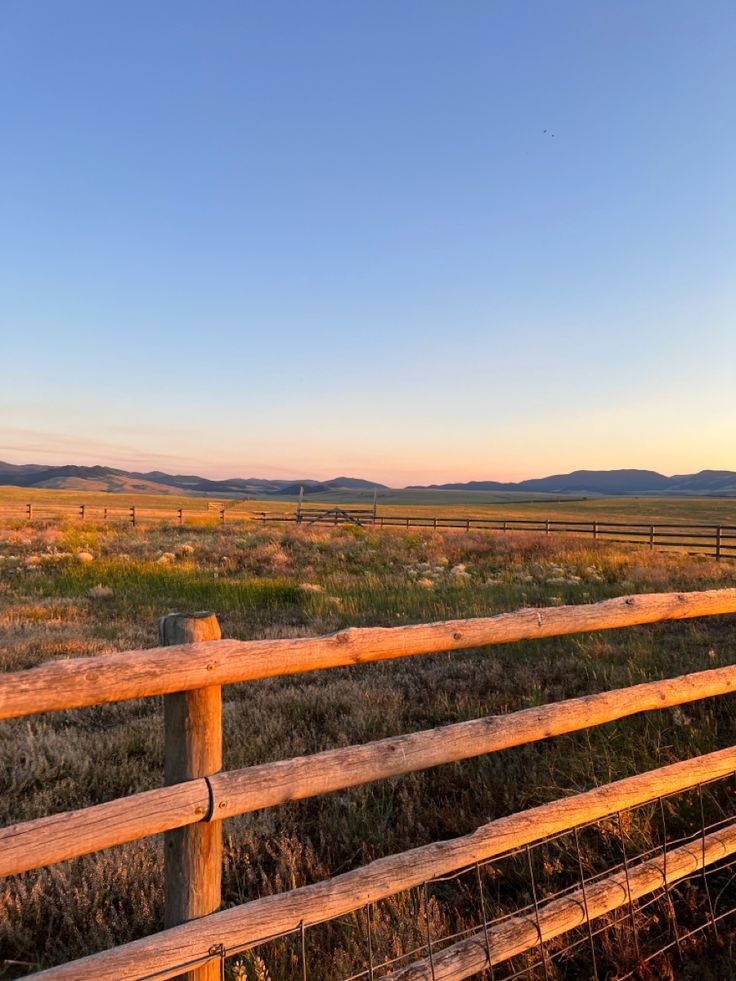 a wooden fence in the middle of a field