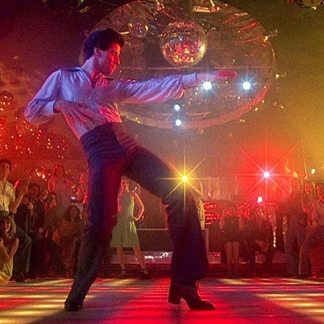 a man and woman dancing on a dance floor with disco balls in the back ground