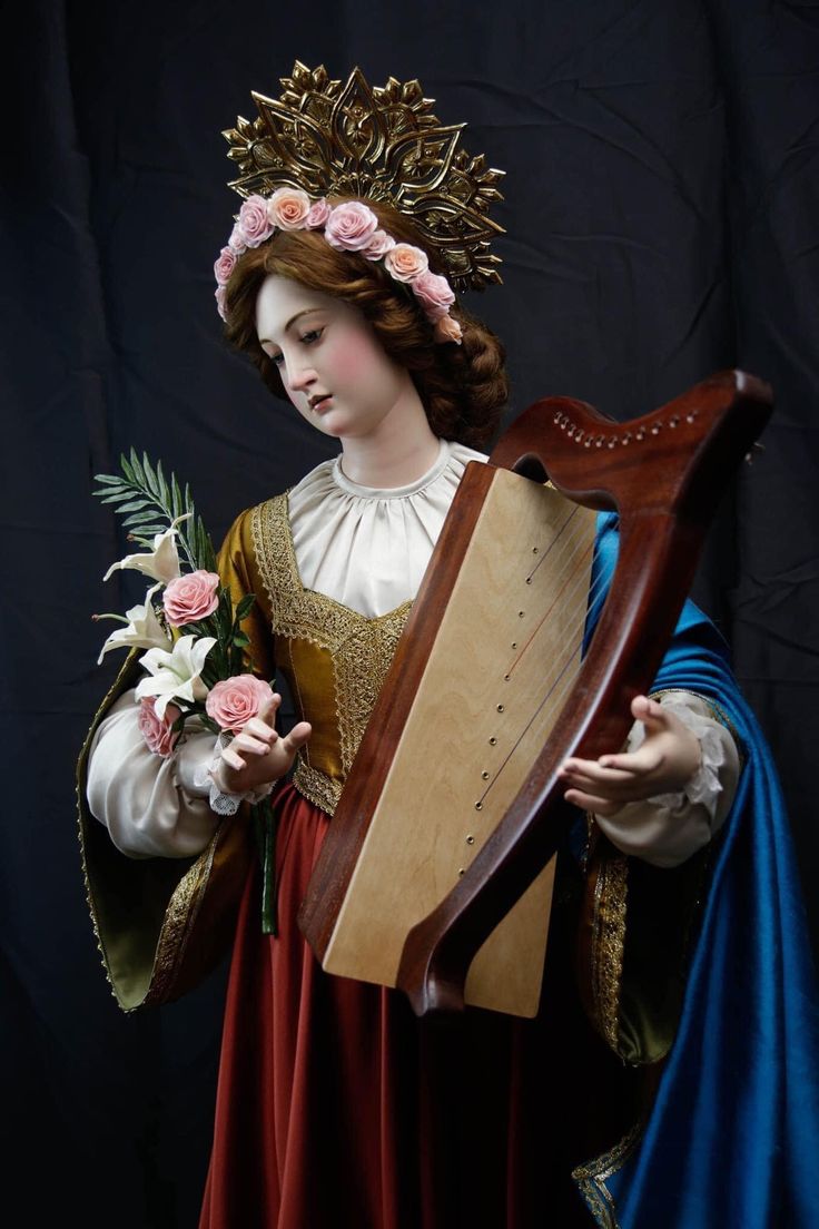 a statue of a woman holding a harp with flowers in her hair and wearing a blue dress