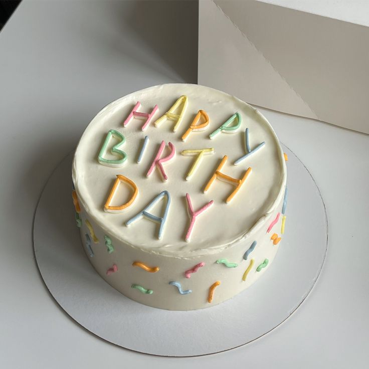 a birthday cake with white frosting and colorful sprinkles that says happy birthday