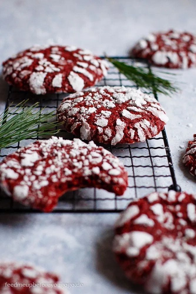 red velvet cookies with white powdered sugar and sprig of rosemary on cooling rack