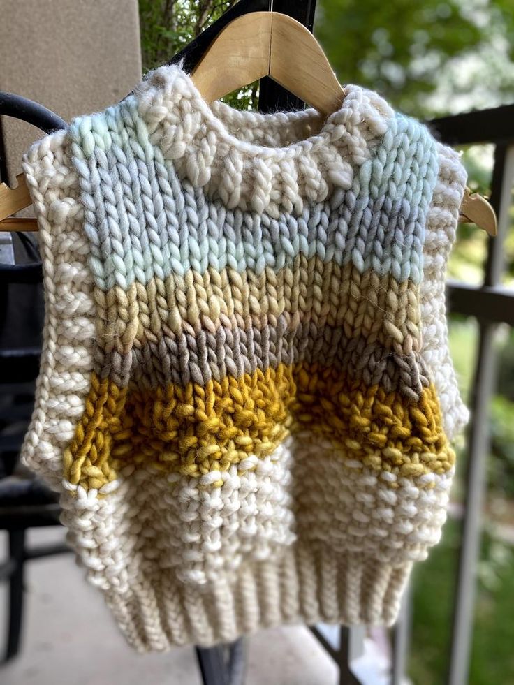 a knitted sweater hanging from a clothes rack on a patio table with chairs in the background