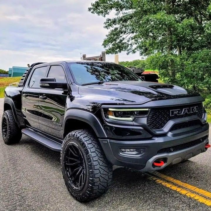 a black truck is parked on the side of the road in front of some trees