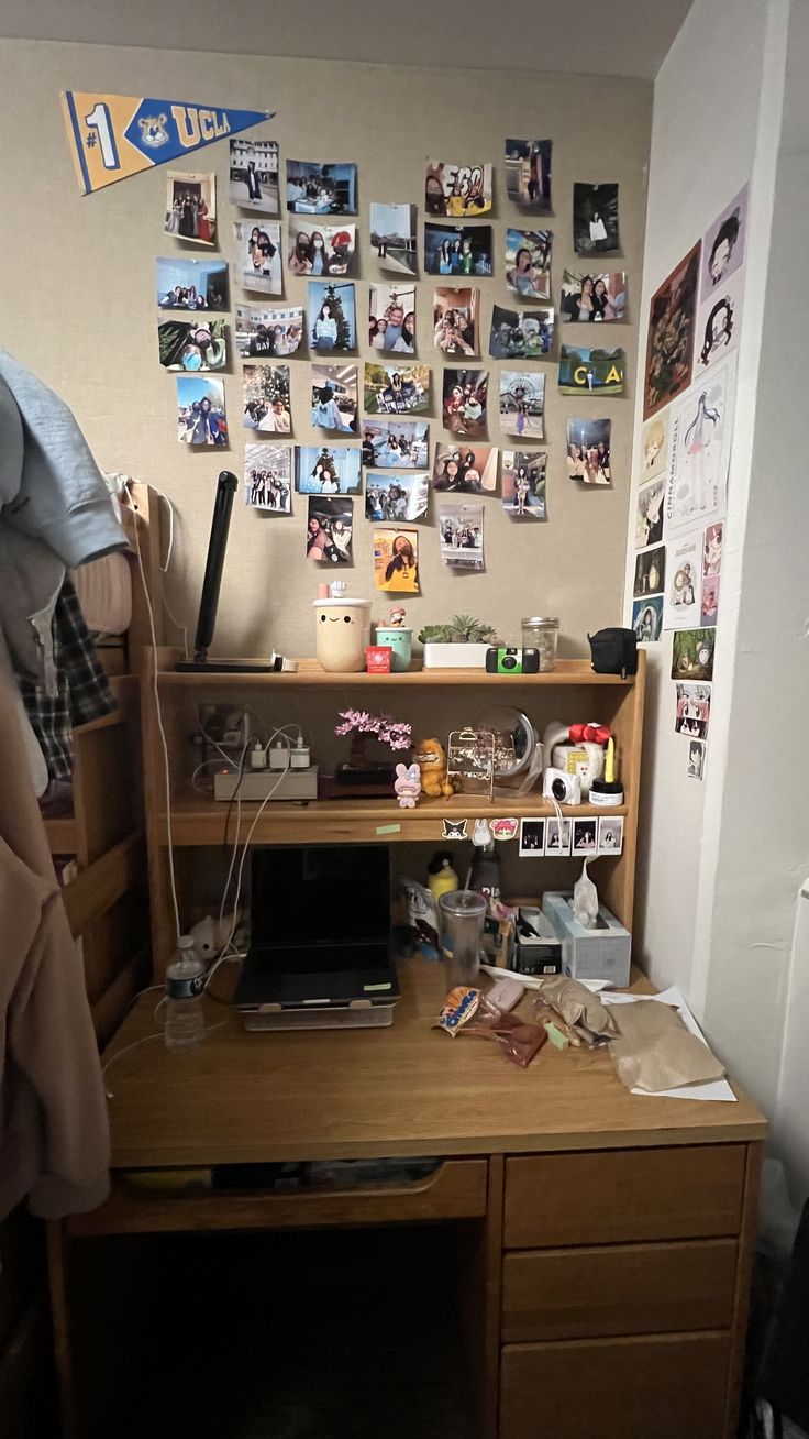 a desk with a computer on top of it in front of a wall covered with pictures