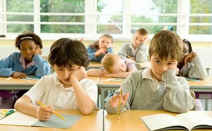 there are many children sitting at desks with books and pencils in their hands