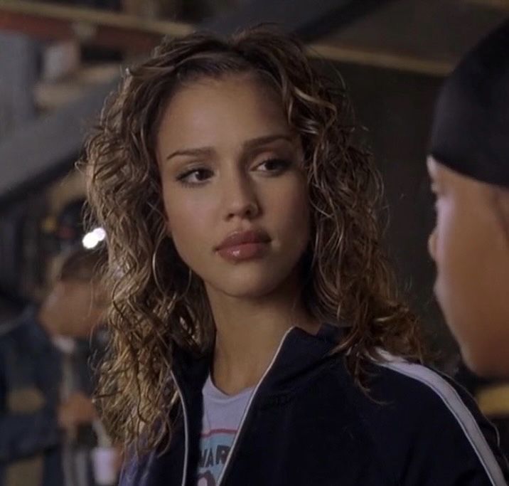 a woman with curly hair is talking to another woman in a baseball cap and jacket