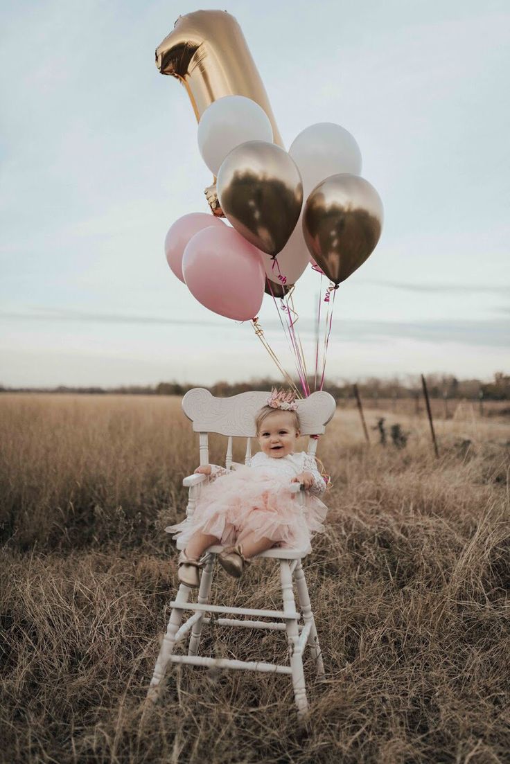 a baby sitting in a chair with balloons