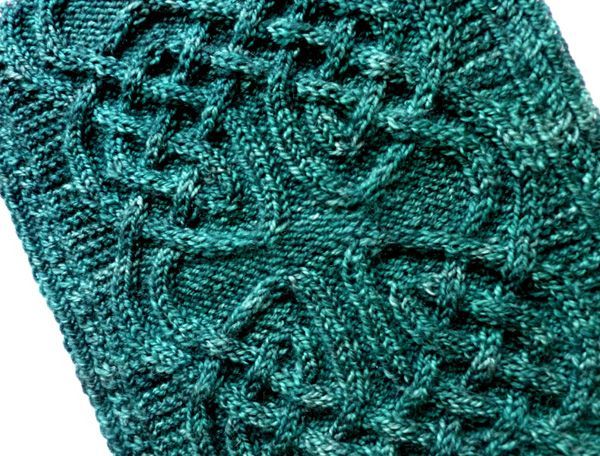 a green knitted dishcloth on a white background with an intricate design in the center