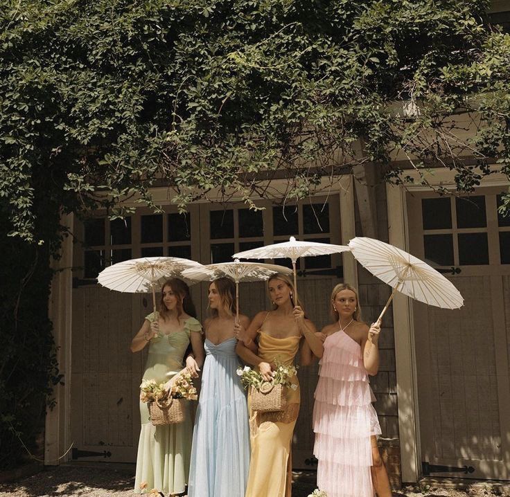 three women standing under umbrellas in front of a building