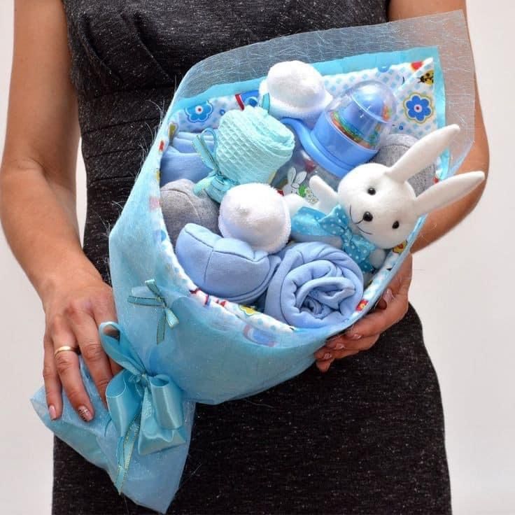 a woman holding a basket filled with blue baby items and stuffed animals in it's hands