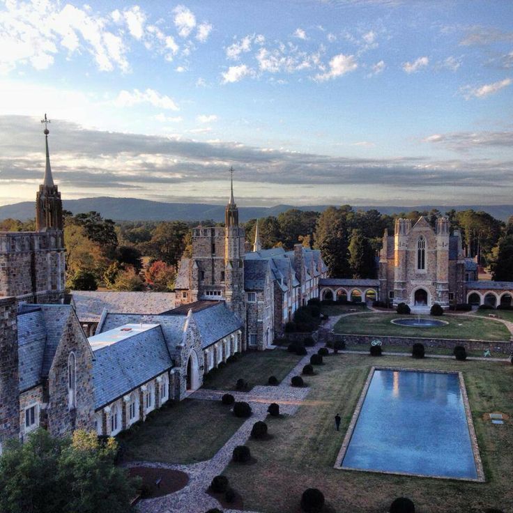 an aerial view of a large building with a pool in the foreground and trees surrounding it