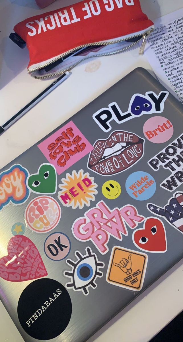 a laptop computer sitting on top of a desk covered in stickers and magnets