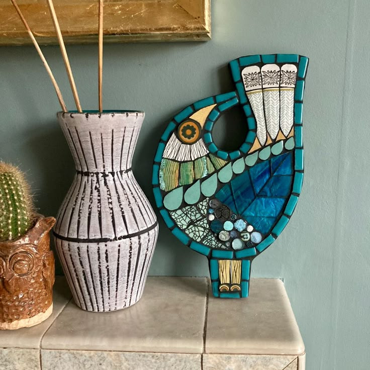 two vases sitting on top of a table next to a cactus and an owl