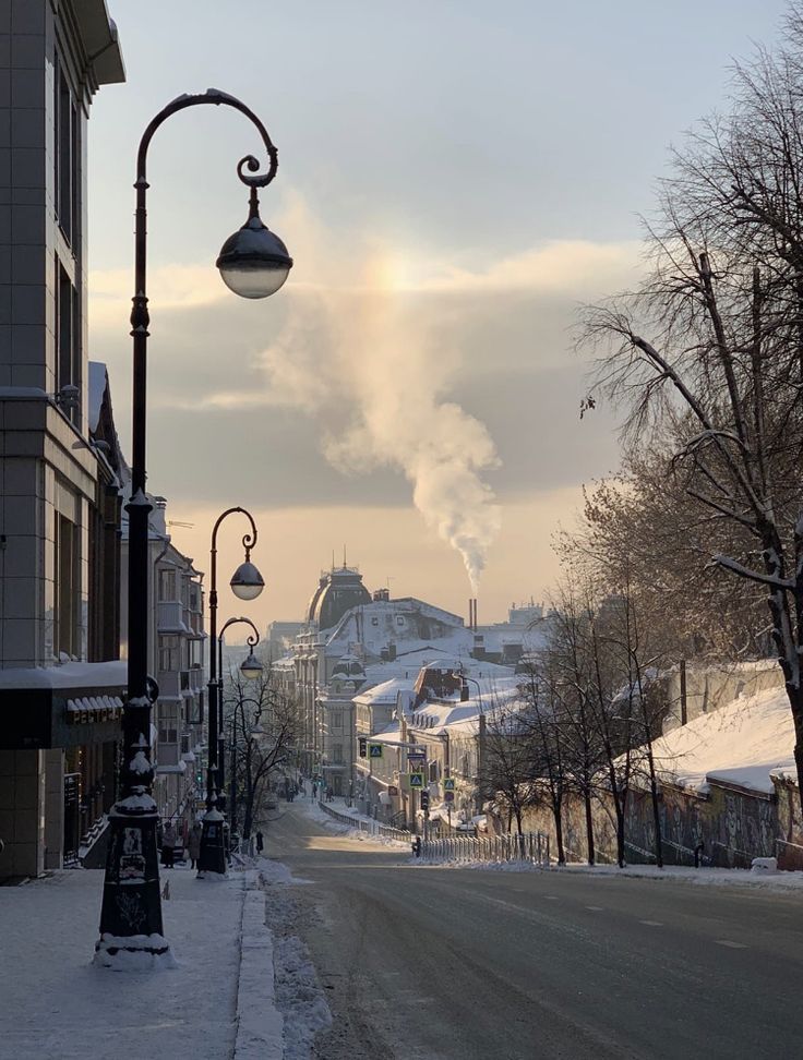 a snowy street lined with buildings and lamps