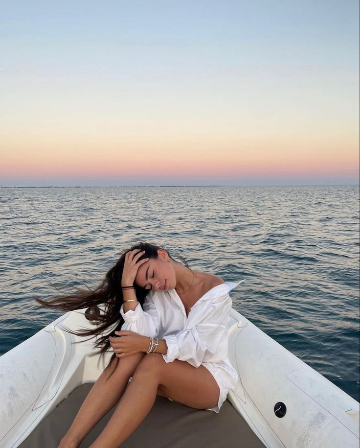 a woman sitting on top of a boat in the ocean