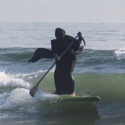 a man riding on top of a surfboard in the ocean while holding onto a pole