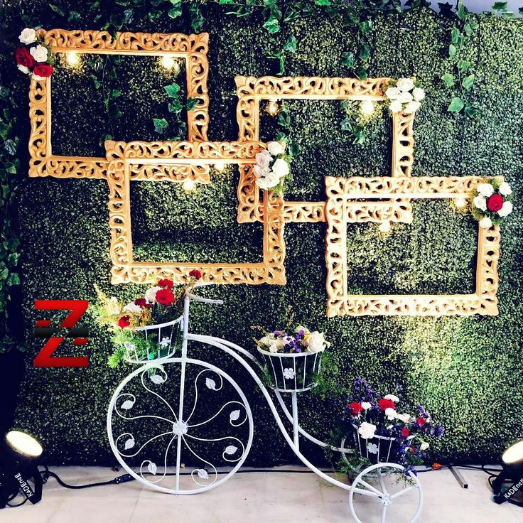 a bike is parked in front of a wall decorated with flowers and frames for photos