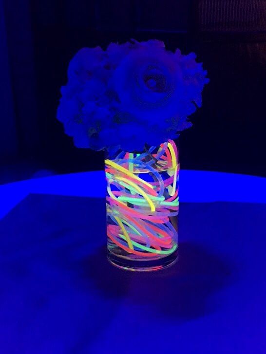 a vase filled with flowers sitting on top of a blue table covered in neon lights