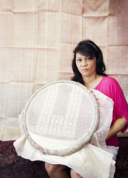 a woman sitting on a bed holding a large piece of cloth