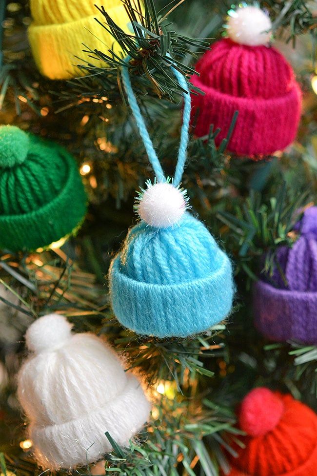 colorful knitted hats hanging from a christmas tree