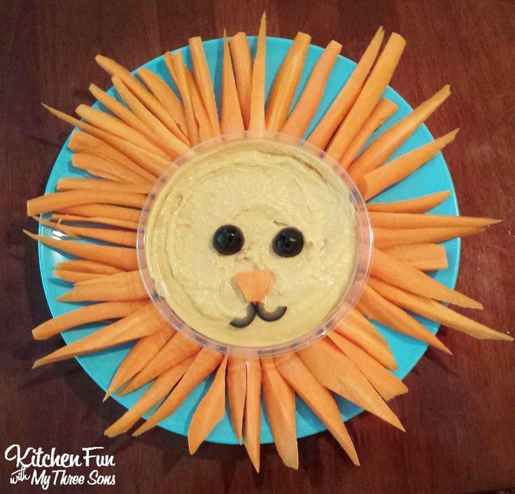 a plate with carrots and dip in the shape of a lion's face