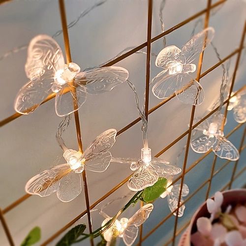 fairy lights are hanging from a wire in front of a potted plant with flowers