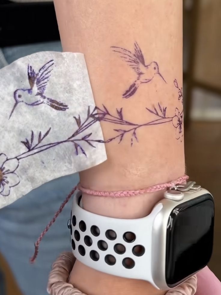 a woman's arm with an apple watch on it and two birds flying over her wrist