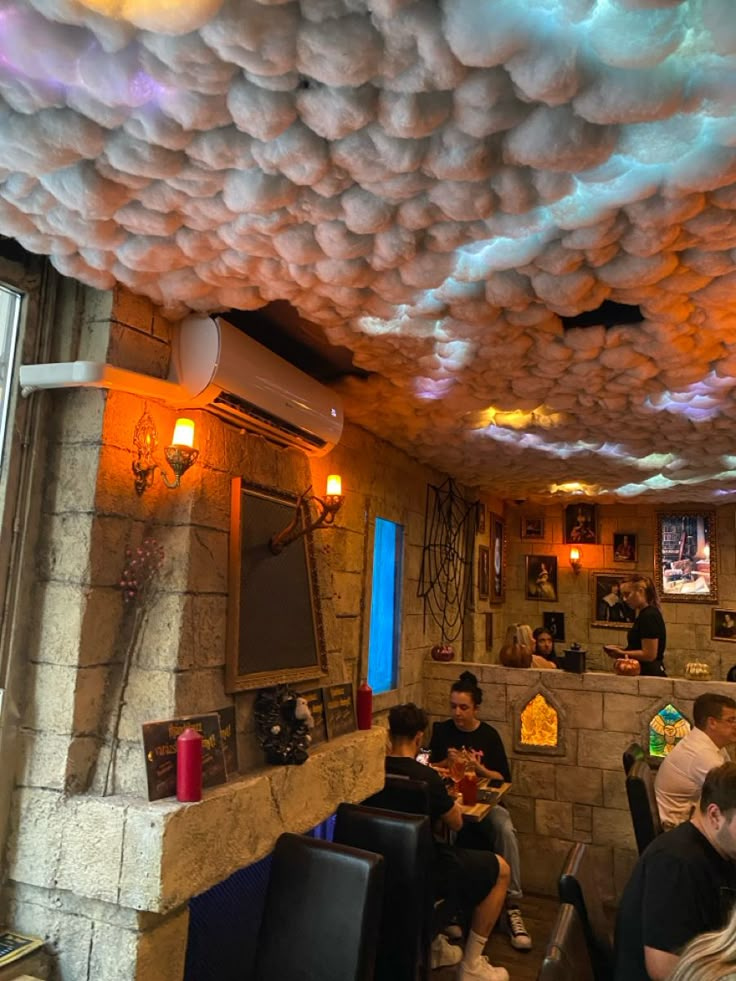 people are sitting at tables in a restaurant with clouds hanging from the ceiling above them