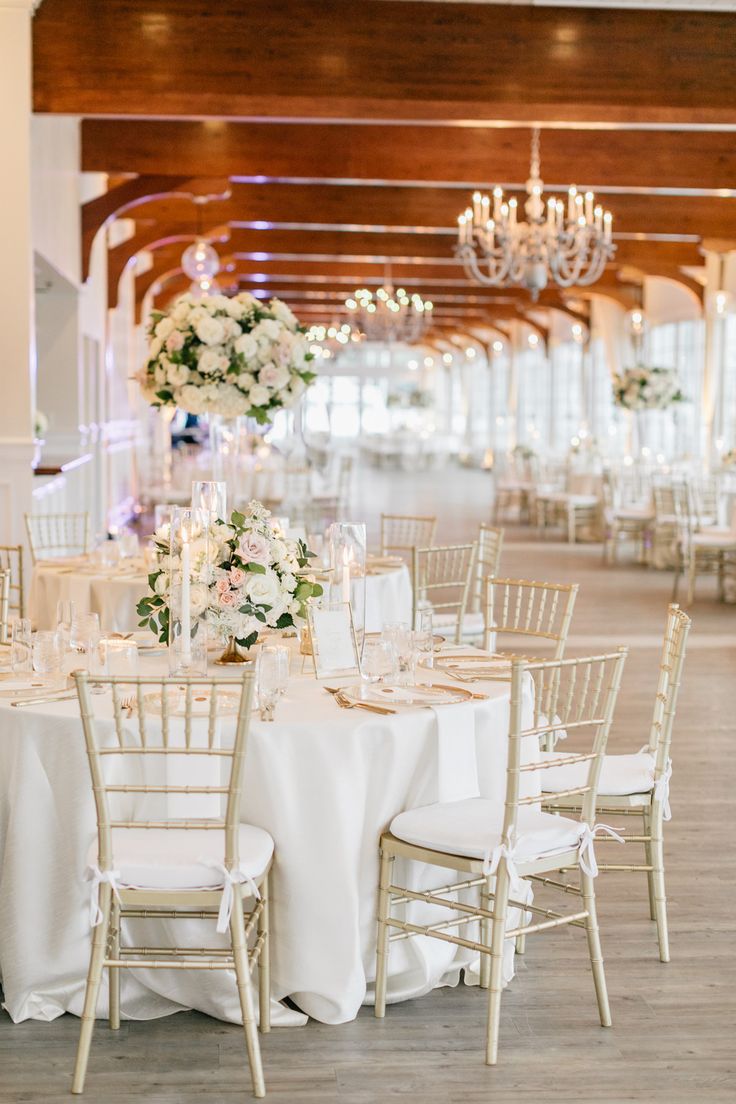 the tables are set up with white linens and gold chairs for an elegant wedding reception