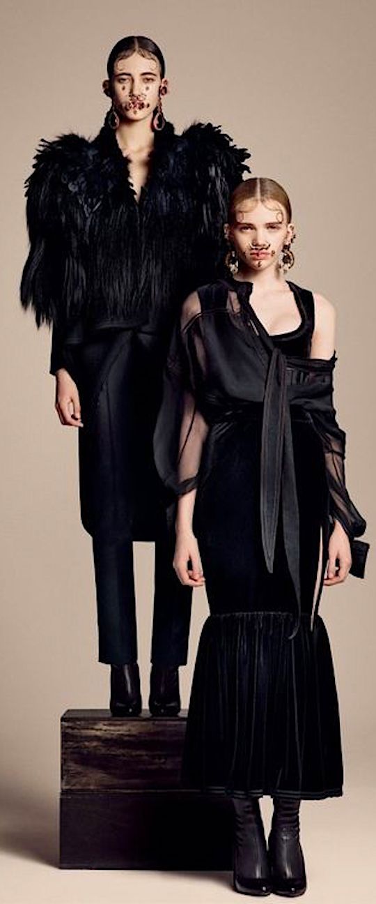 two women standing next to each other in black outfits