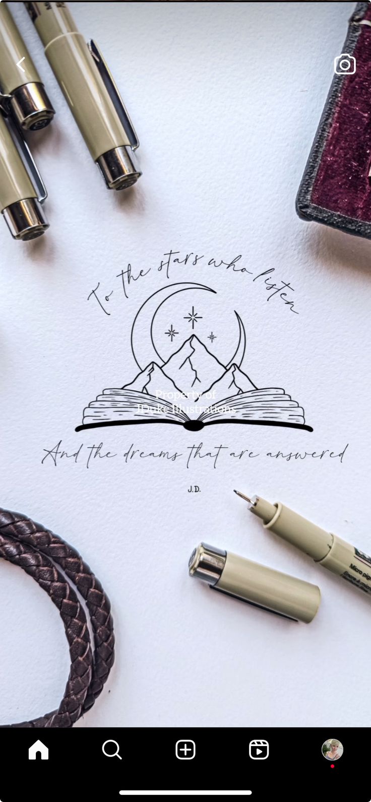 an open book sitting on top of a table next to fountain pens