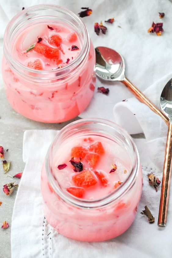 two mason jars filled with yogurt and strawberries on top of a table