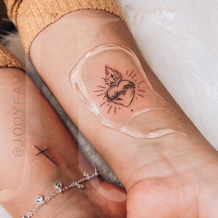 two people with tattoos on their arm and wrist, one is holding the other's hand